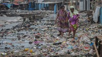 Warga melintasi tumpukan sampah yang terbawa ombak di Teluk Labuan, Pandeglang, Banten, Senin (7/2/2022).