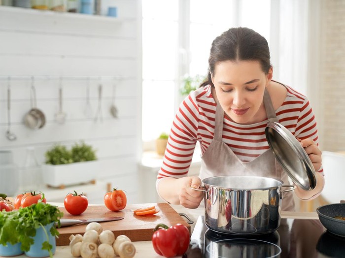 ilustrasi wanita jago masak Healthy food at home. Happy woman is preparing the proper meal in the kitchen.
