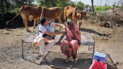 Seorang nakes melakukan vaksinasi ke pelosok India di tengah terik matahari sembari menggendong bayinya. Ini dilakukan demi sukses vaksinasi di India.