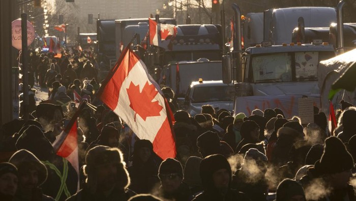 Protesters walk around trucks parked in the downtown area in protest of COVID-19 restrictions, in Ottawa, Ontario, Saturday, Feb. 5, 2022. (Adrian Wyld/The Canadian Press via AP)