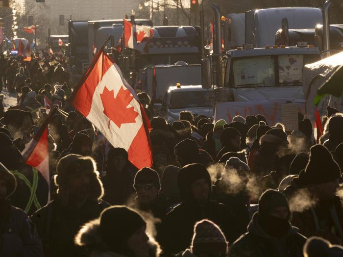 Protesters walk around trucks parked in the downtown area in protest of COVID-19 restrictions, in Ottawa, Ontario, Saturday, Feb. 5, 2022. (Adrian Wyld/The Canadian Press via AP)