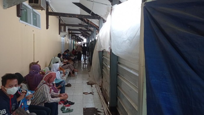 Warga mengantre di antara proyek pembangunan poliklinik RSUD dr Soekardjo yang terhenti akibat refokusing anggaran