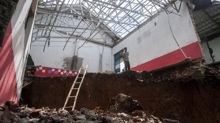 Penjaga sekolah melihat kondisi ruang kelas yang amblas di MTs Ar Ribathiyah, Lebak, Banten, Rabu (9/2/2022). Dua bangunan ruang kelas dan perpustakaan di sekolah tersebut amblas akibat longsor dengan kedalaman 15 meter yang terjadi setelah hujan deras. ANTARA FOTO/Muhammad Bagus Khoirunas/tom.