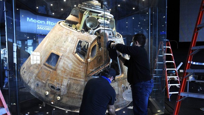 Workers open the glass case enclosing the Apollo 16 lunar capsule at the U.S. Space and Rocket Center in Huntsville, Ala., on Tuesday, Feb. 1, 2022. Following a break in routine maintenance because of the COVID-19 pandemic, the museum is sprucing up the antique spaceship before events marking the 50th anniversary of its flight to the moon in 1972. (AP Photo/Jay Reeves)