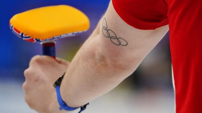 Magnus Nedregotten, of Norway, holds a brush and has an Olympic rings tattoo on his arm during the mixed doubles curling match against the Czech Republic at the Beijing Winter Olympics Wednesday, Feb. 2, 2022, in Beijing. (AP Photo/Brynn Anderson)