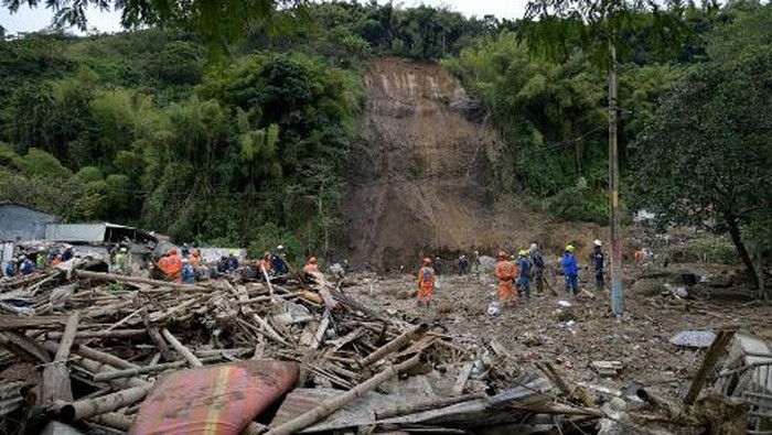 Rescuers look the debris after a landslide caused by heavy rains in Pereira, Risaralda department, Colombia, on February 8, 2022. - The landslide left 7 dead and 29 injured in the Pereira neighbourhood on Tuesday, due to heavy rains in recent days, according to authorities. (Photo by Luis ROBAYO / AFP)