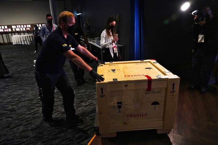 A mover pushes a box holding a Quran owned by U.S. President Thomas Jefferson as it leaves the American pavilion at Dubai Expo 2020 in Dubai, United Arab Emirates, Wednesday, Feb. 9, 2022. The Quran, on its first trip ever outside of the U.S. since being bought by Jefferson, had been on display at the Expo under constant guard. It was packed Wednesday to be returned to the Library of Congress. (AP Photo/Jon Gambrell)