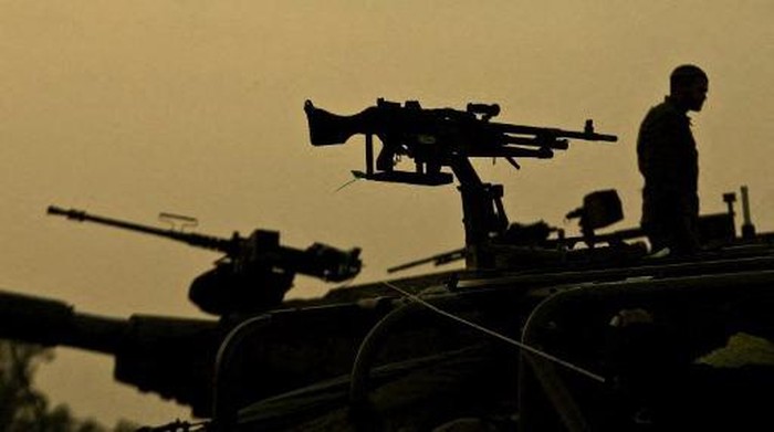 An Israeli soldier stands on top of his tank  at an Israeli army deployment area near the Israel-Gaza Strip border, before troop start to prepare their tanks for a potential ground operation in the Palestinian Gaza Strip on November 19, 2012. The Israeli cabinet gave its green light for the recruitment of up to 75,000 reservists, Channel 2 television said, amid signs that Israel was gearing up for a ground offensive in Gaza.  AFP PHOTO / JACK GUEZ (Photo by JACK GUEZ / AFP)
