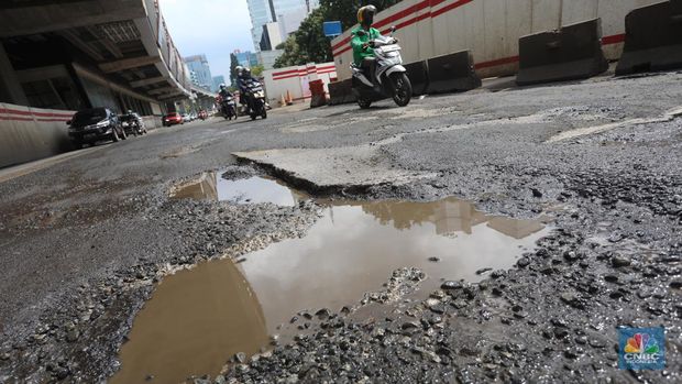 Kendaraan melintasi jalan yang rusak di kawasan H. R. Rasuna Said, Jakarta, Rabu (9/2/2022). Jalan rusak ini sangat berbahaga bagi pengendara terlebih saat hujan turun. (CNBC Indonesia/Andrean Kristianto)