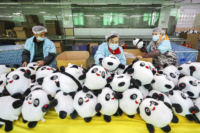 Workers at a factory manufacture Bing Dwen Dwen stuffed dolls, the mascot of 2022 Winter Olympics, in Jinjiang city in southeastern Chinas Fujian province Tuesday, Feb. 8, 2022. Long queues have formed for scarce 2022 Winter Olympic souvenirs, especially stuffed versions of Games mascot Bing Dwen Dwen, a panda in a winter coat. The Beijing Olympic organizing committee have asked souvenir factories to make more, the official Xinhua News Agency reported. Many reopened this week after shutting down for two weeks or more during the Lunar New Year holiday. (Chinatopix via AP)