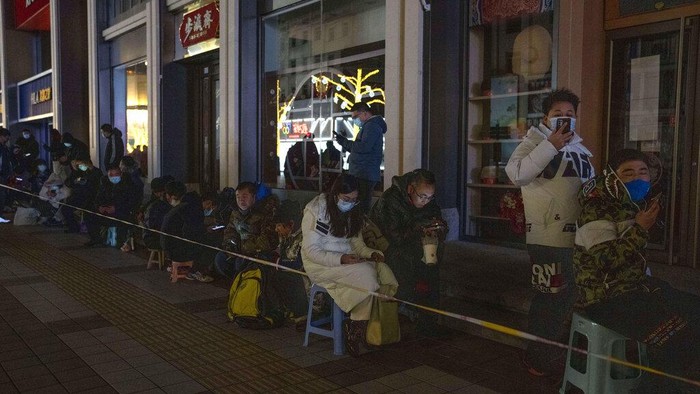 People line up along the darkened Wangfujing pedestrian mall outside the Gongmei Emporium to queue overnight for a chance to buy the 2022 Winter Olympics mascot Bing Dwen Dwen in Beijing on Tuesday, Feb. 8, 2022. A long line have persisted in the past days to snap up scarce 2022 Winter Olympic souvenirs, especially stuffed versions of Games mascot Bing Dwen Dwen, a panda in a winter coat. (AP Photo/Ng Han Guan)