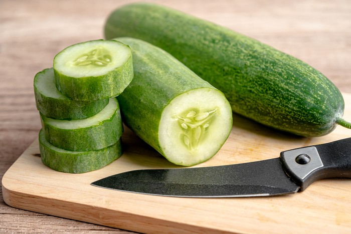 Cucumber vegetable food cut in slice and knife on cutting board for cooking in kitchen.