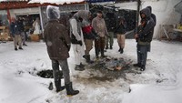 Pria Afghanistan menghangatkan diri di sekitar api unggun selama cuaca bersalju di pasar yang ramai di Kabul, Afghanistan, Minggu, (6/2/2022). Afghanistan hidup dari bantuan kemanusiaan.