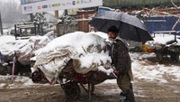 Pedagang kaki lima mendorong barang-barangnya yang tertutup salju di Kabul, Afghanistan, Minggu, (6/2/2022). Usai direbut kembali oleh Taliban, Afghanistan masuk ke jurang kemiskinan. Setidaknya PBB mengucurkan bantuan hingga Rp 63 triliun yang merupakan bantuan terbesar dalam sebuah krisis kemanusiaan.