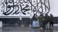 Gerilyawan Taliban memakan cemilan dari PKL dengan latar bendera Taliban, Selasa (8/2/2022). Aset Afghanistan di luar negeri dibekukan oleh sejumlah negara dan lembaga asing sebagai respon kepemimpinan Taliban. Pembekuan aset yang mencapai Rp 143 triliun tersebut membuat Afghanistan mengalami krisis kemanusiaan.