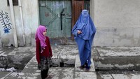 Perempuan berburka dengan anaknya berdiri di luar rumah di Kabul, Selasa (8/2/2022). Bantuan kemanusiaan yang mengalir sampai ke warga miskin dikecualikan dari embargo dan pembekuan aset Afghanistan di luar negeri.