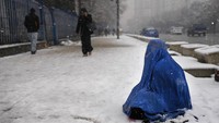 Perempuan berburka mengemis di jalanan bersalju Ibu Kota Kabul, Minggu (6/2/2022). Kemiskinan menjadi pemandangan sehari-hari di Kabul dan Afghanistan. Menurut data PBB, bantuan senilai US$ 1,6 miliar atau setara Rp 23 trilun bakal disalurkan ke Afghanistan pada Februari ini.