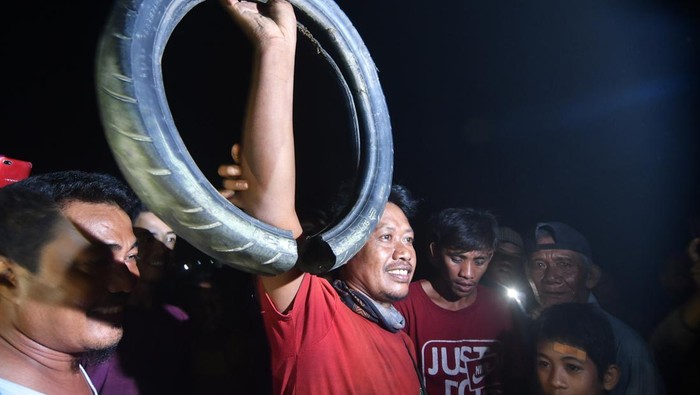 Seekor buaya liar yang terjerat ban bekas sepeda motor masuk ke dalam air di Sungai Palu, Sulawesi Tengah, Minggu (29/9/2019).