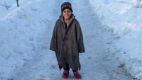 Bocah Khasmir berpose di tengah jalan bersalju di Budgam, India, 27 Januari 2022. Kesederhanaan bukan penghalang untuk merasakan kebahagiaan. (Photo by Faisal Bashir / SOPA Images/Sipa USA)