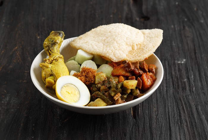 Lontong Cap Go Meh. Indonesia Peranakan Dish of Rice Cake Soup or Lontong Sayur with Opor Ayam Chicken Curry, Spicy Chayote Curry, SAmbel Goreng Ati Kentang, and Egg. Served with Shrimp Cracker