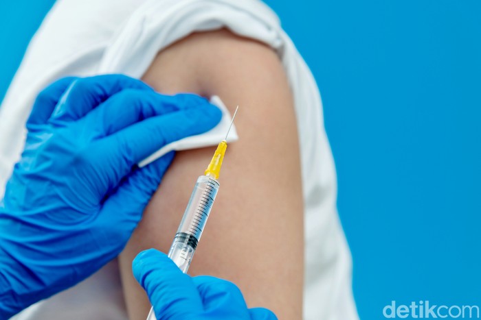 Doctor vaccinating for a boy on blue background.