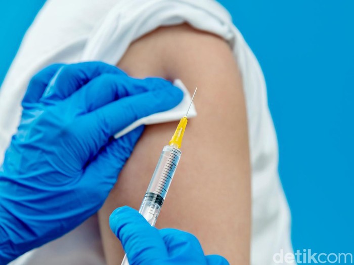 Doctor vaccinating for a boy on blue background.