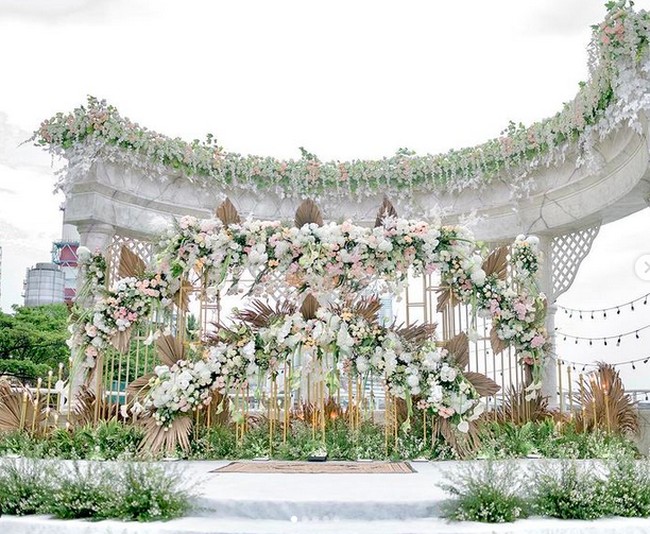 Di luar keromantisan pasangan yang berbahagia, dekorasi acara juga tak kalah mencuri perhatian. Backdrop penuh rangkaian bunga bergaya rustic turut menyemarakkan suasana. (Foto: Instagram/@hijrahwedding)