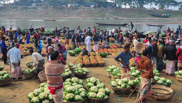 Local sellers offer vegetables cultivated for their, during the sell winter vegetables on  outside market  at the bank of the Surma river, after sunrise. On February 8, 2022 in   Kanaighat Upazila, Bangladesh. (Photo by Md Rafayat Haque Khan/ Eyepix Group)