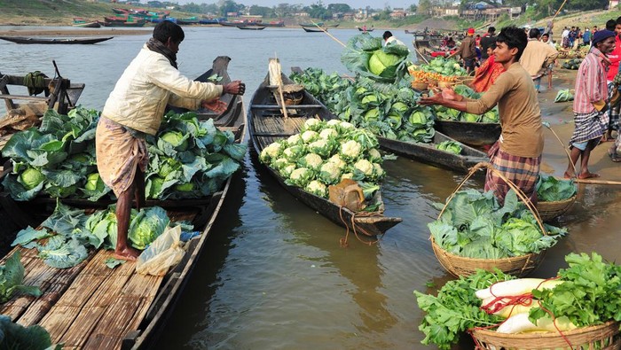 Local sellers offer vegetables cultivated for their, during the sell winter vegetables on  outside market  at the bank of the Surma river, after sunrise. On February 8, 2022 in   Kanaighat Upazila, Bangladesh. (Photo by Md Rafayat Haque Khan/ Eyepix Group)