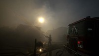 Tampak petugas berjibaku memadamkan api yang merembet ke rumah.