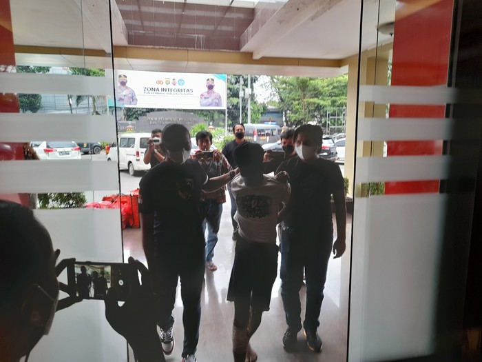 Polisi saat membawa salah satu terduga pelaku pembunuhan di TPU Kober (Marteen-detikcom)