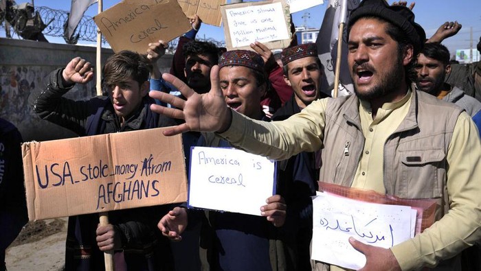 Afghan protesters hold placards and shout slogans against U.S. during a protest condemning President Joe Bidens decision, in Kabul, Afghanistan, Saturday, Feb. 12, 2022. President Biden signed an executive order, Friday, Feb. 11, to create a pathway to split $7 billion in Afghan assets frozen in the U.S. to fund humanitarian relief in Afghanistan and to create a trust fund to compensate Sept. 11 victims. (AP Photo/Hussein Malla)