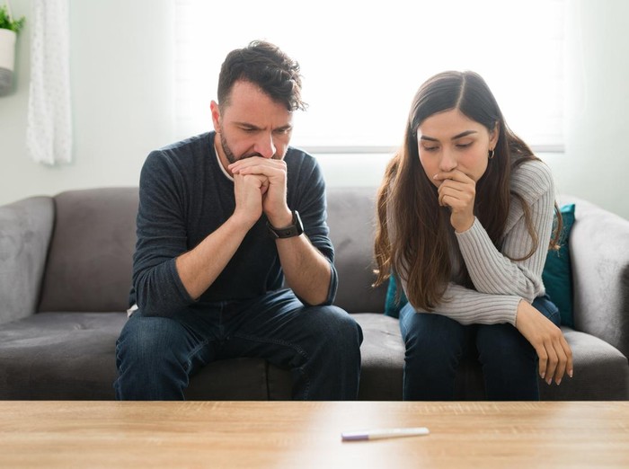 Attractive couple feeling scared and anxious while waiting for the positive or negative results of a home pregnancy test
