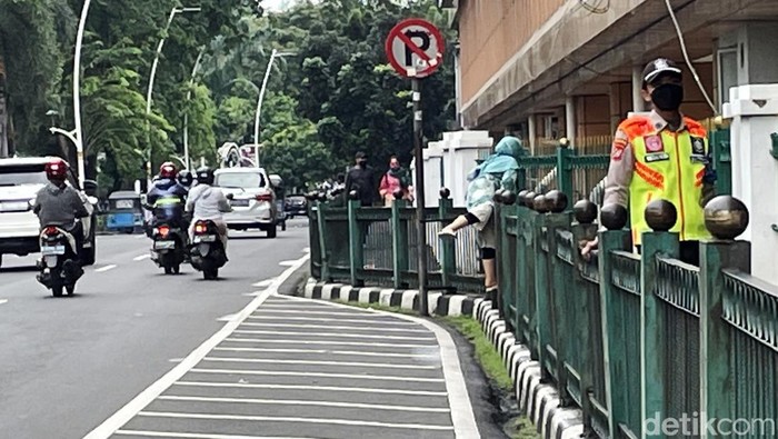 Sejumlah emak-emak yang merupakan penumpang KRL melakukan aksi nekat melompati pagar pembatas trotoar di Stasiun Cikini, Jakarta, Senin (14/02/2022).