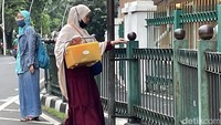 Seorang emak-emak bersiap melompati pagar pembatas trotoar di Stasiun Cikini, Jakarta, Senin (14/2/2022).