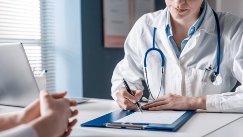 Doctor sitting at desk and writing a prescription for her patient