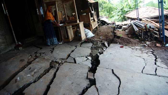 Dua warga duduk di dekat jalan desa yang terbelah akibat bencana tanah bergerak di Desa Dermasuci, Kabupaten Tegal, Jawa Tengah, Senin (14/2/2022). Menurut data pemerintah desa setempat, jumlah rumah yang rusak akibat bencana tanah bergerak bertambah dari 97 rumah menjadi 238 rumah dan mengakibatkan sejumlah akses jalan desa terputus. ANTARA FOTO/Oky Lukmansyah/pras.