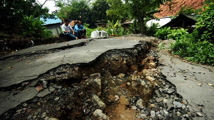 Dua warga duduk di dekat jalan desa yang terbelah akibat bencana tanah bergerak di Desa Dermasuci, Kabupaten Tegal, Jawa Tengah, Senin (14/2/2022). Menurut data pemerintah desa setempat, jumlah rumah yang rusak akibat bencana tanah bergerak bertambah dari 97 rumah menjadi 238 rumah dan mengakibatkan sejumlah akses jalan desa terputus. ANTARA FOTO/Oky Lukmansyah/pras.