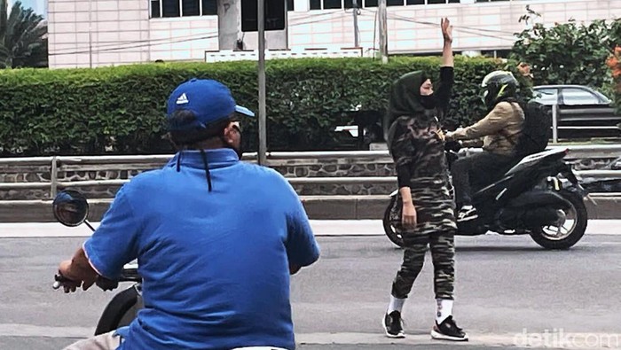 Seorang wanita berseragam loreng menjadi polisi cepek yang membantu mengatur lalu lintas di Jalan Gatot Subroto, Jakarta. Begini aksinya.