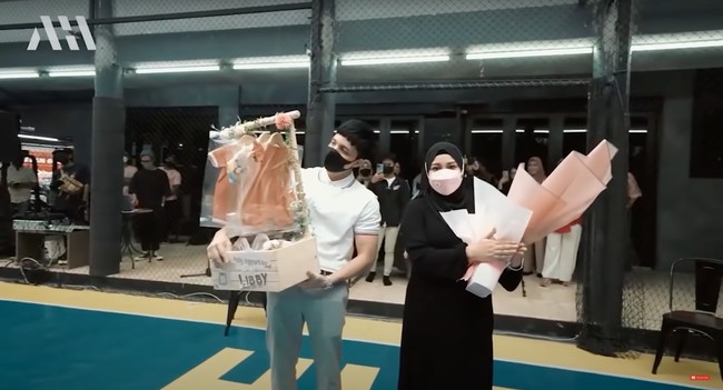 Setelah melihat sambutan tarian, Atta dan Aurel pun diberikan hadiah berupa buket bunga dan beberapa pakaian untuk baby A yang sudah dihias. Walaupun masih terlihat bingung, namun keduanya tampak bahagia dan senang menerima kejutan tersebut. Foto: YouTube/AH