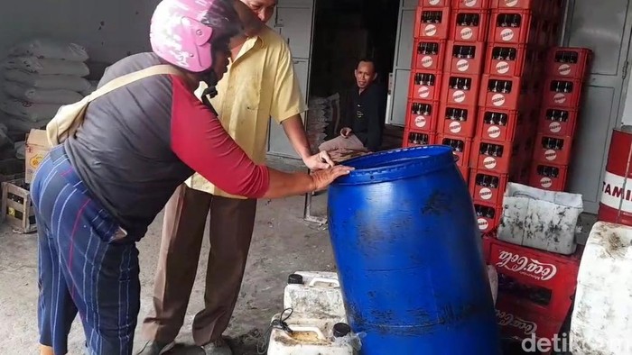 Pembeli di Brebes memeriksa drum minyak goreng di salah satu toko sembako.