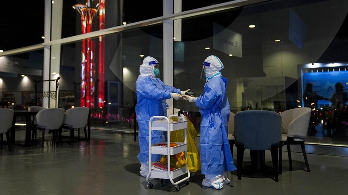 Two workers scan a tube after collecting swab samples from tables and chairs for COVID-19 testing at the main media center of the 2022 Winter Olympics, Thursday, Feb. 10, 2022, in Beijing. (AP Photo/Jae C. Hong)