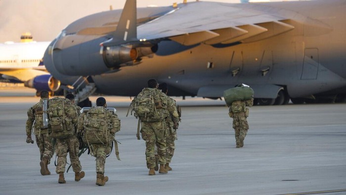 Members of the 82nd Airborne Division of the U.S. Army walk on the tarmac at Pope Field ahead of deployment to Poland from Fort Bragg, N.C. on Monday, Feb. 14, 2022. They are among soldiers the Department of Defense is sending in a demonstration of American commitment to NATO allies worried at the prospect of Russia invading Ukraine.  (AP Photo/Nathan Posner)