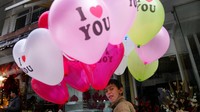 Seorang bocah Afghanistan memberi isyarat saat dia menjual balon Hari Valentine di sebuah jalan di Kabul, Afghanistan. Penguasa Taliban kini tengah menangani transisi dari perang ke perdamaian.