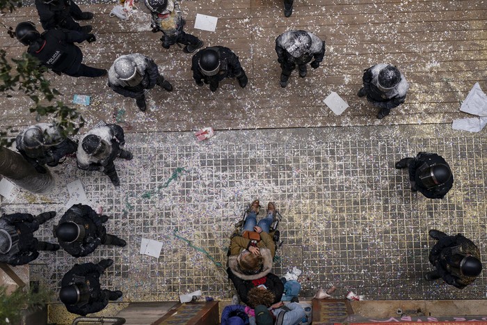 Riot police officers covered in flour that was thrown at them, detain an anti-evictions activist before breaking into Ganna Drozdovych's apartment to evict her and her family from their apartment for non-payment rent in Barcelona, Spain, Monday, Feb. 14, 2022. Ganna Drozdovych, 48, a a hotel worker who was on a furlough temporary workforce reduction program during the pandemic was evicted along with her unemployed partner and two sons. (AP Photo/ Joan Mateu Parra)