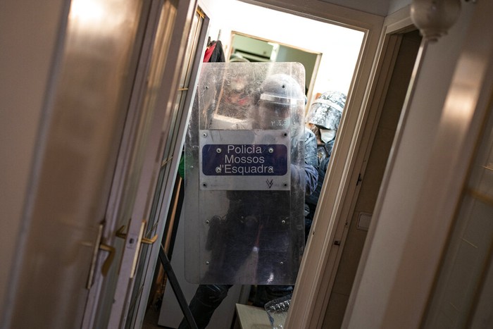 Riot police officers covered in flour that was thrown at them, detain an anti-evictions activist before breaking into Ganna Drozdovych's apartment to evict her and her family from their apartment for non-payment rent in Barcelona, Spain, Monday, Feb. 14, 2022. Ganna Drozdovych, 48, a a hotel worker who was on a furlough temporary workforce reduction program during the pandemic was evicted along with her unemployed partner and two sons. (AP Photo/ Joan Mateu Parra)