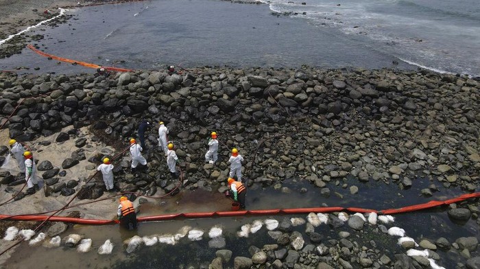 A worker holds a type of skimmer that collects oil waste during a clean-up campaign on Pocitos Beach in Ancon, Peru, Tuesday, Feb. 15, 2022. One month later, workers continue the clean-up on beaches after contamination by a Repsol oil spill. (AP Photo/Martin Mejia)