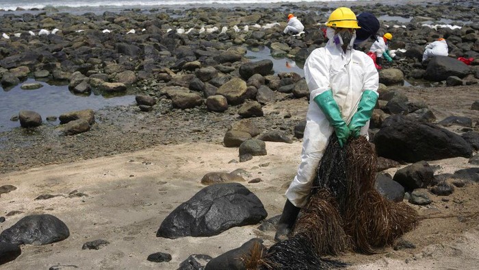 A worker holds a type of skimmer that collects oil waste during a clean-up campaign on Pocitos Beach in Ancon, Peru, Tuesday, Feb. 15, 2022. One month later, workers continue the clean-up on beaches after contamination by a Repsol oil spill. (AP Photo/Martin Mejia)