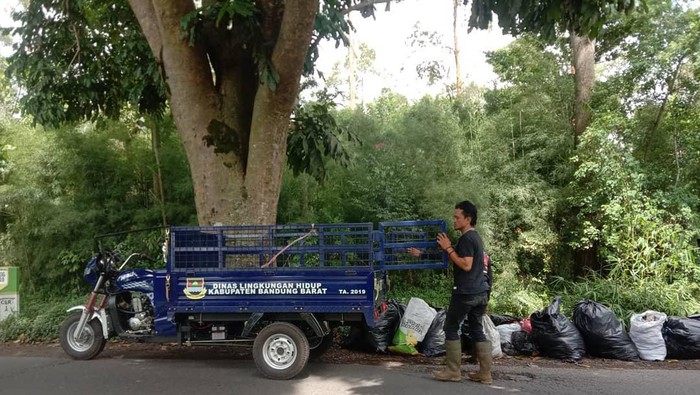 Warga tengah mengangkut sampah di lingkungannya.