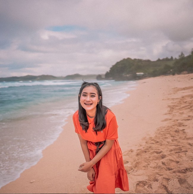 Menghabiskan waktu untuk berlibur ke pantai, Yeni memilih tampil simple mengenakan rok berwarna oranye. Rambutnya terlihat rapih dengan diikat setengah. Sambil tersenyum, Yeni terlihat begitu bahagia. Foto: Instagram/@yeniinka